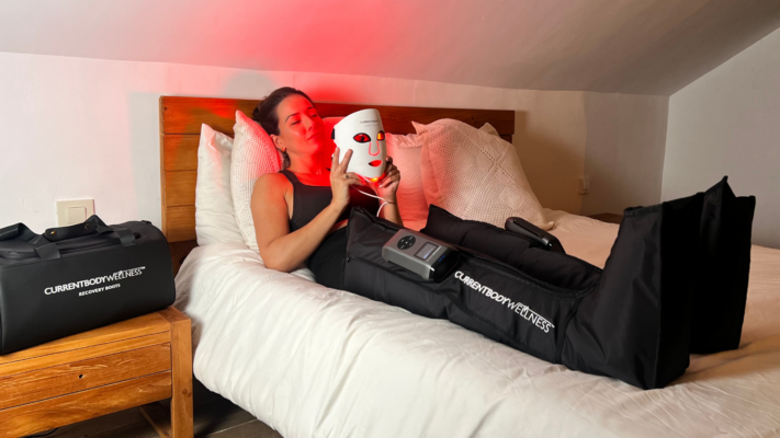 Carmen Bauzá con máscara LED facial de luz roja y botas de presoterapia CurrentBody en casa.